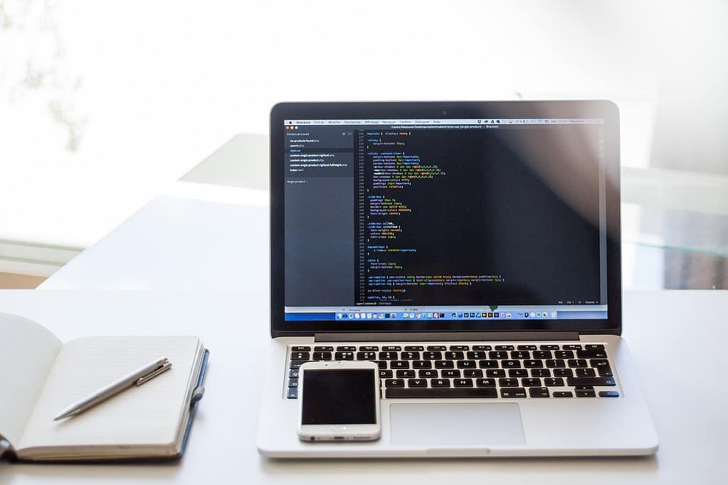 A notebook next to a laptop showing code